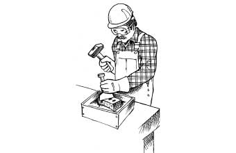 Person cutting a brick wearing gloves, goggles and a hard hat