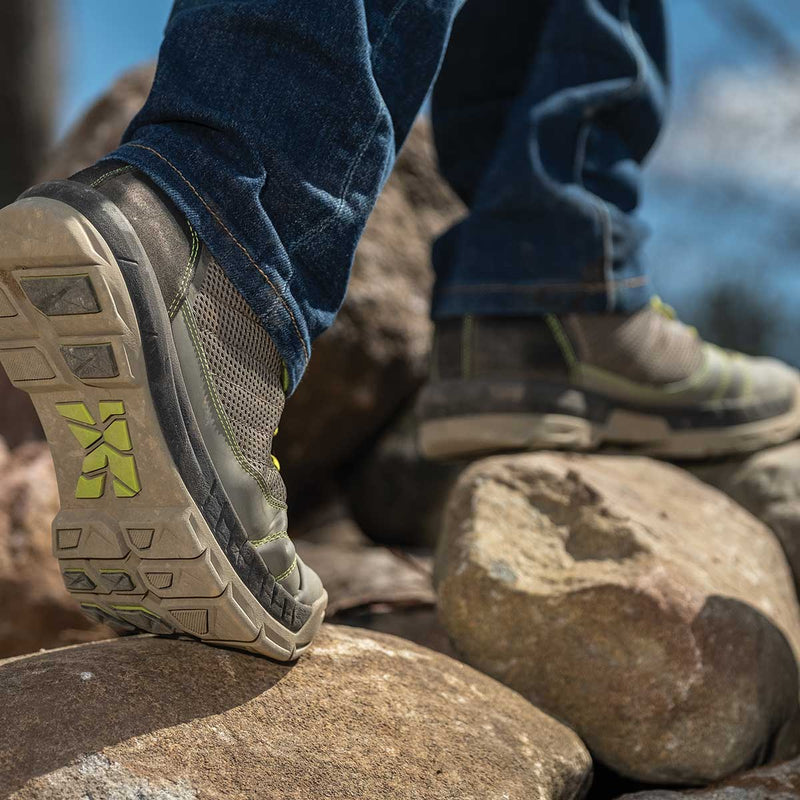 Person wearing grey and green Kujo Yardwear Yard Shoes while walking on rocks