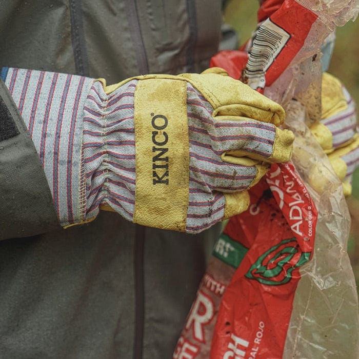 Person wearing Kinco 1917 Safety Cuff Leather Gloves while picking up trash