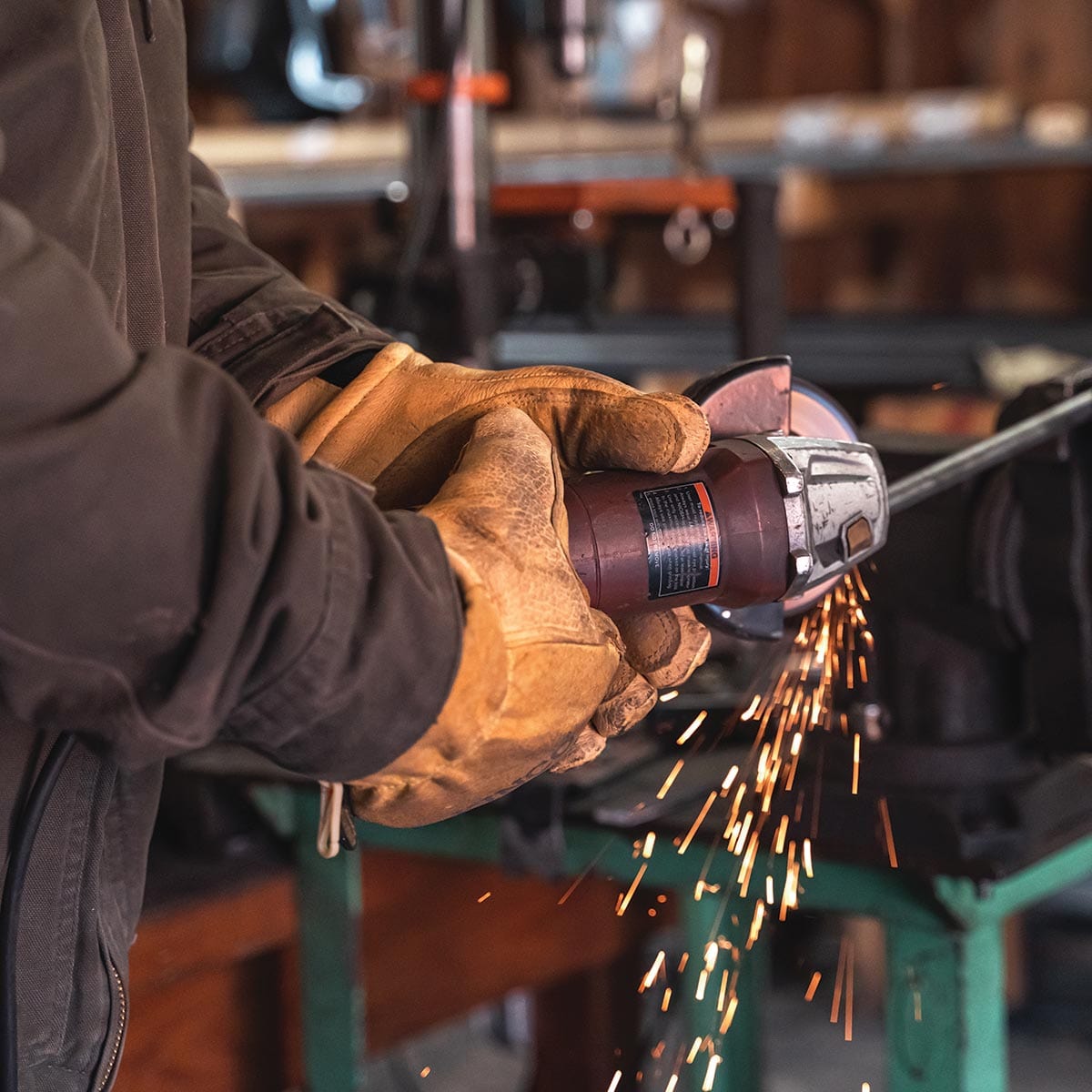 Man wearing Kinco 901 gloves while grinding metal rod