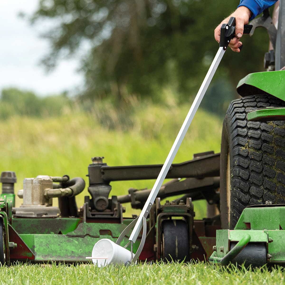 Gemplers Reacher Pickup Tool being used by person sitting on mower+++Gemplers Reacher Pickup Tool being used by person sitting on mower