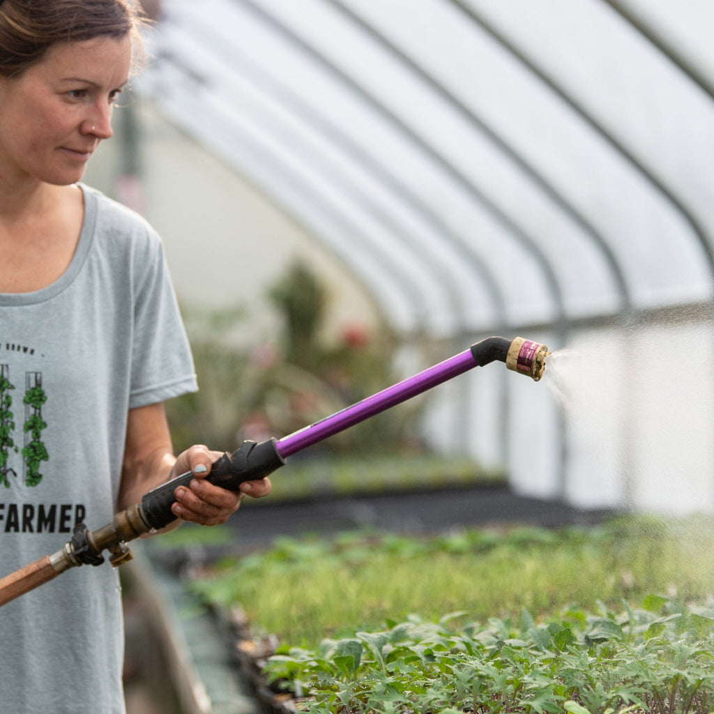 Woman using Fine Fogg-It-Nozzle on end of wand in greenhouse+++Woman using Fine Fogg-It-Nozzle on end of wand in greenhouse