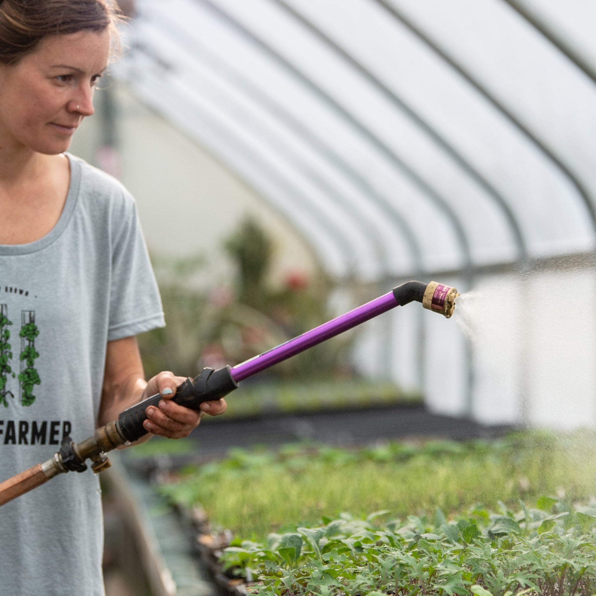 Woman using Fine Fogg-It-Nozzle on end of wand in greenhouse+++Woman using Fine Fogg-It-Nozzle on end of wand in greenhouse