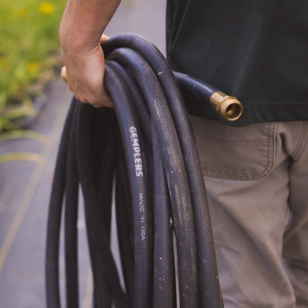 Landscape professional carrying coiled black hose.