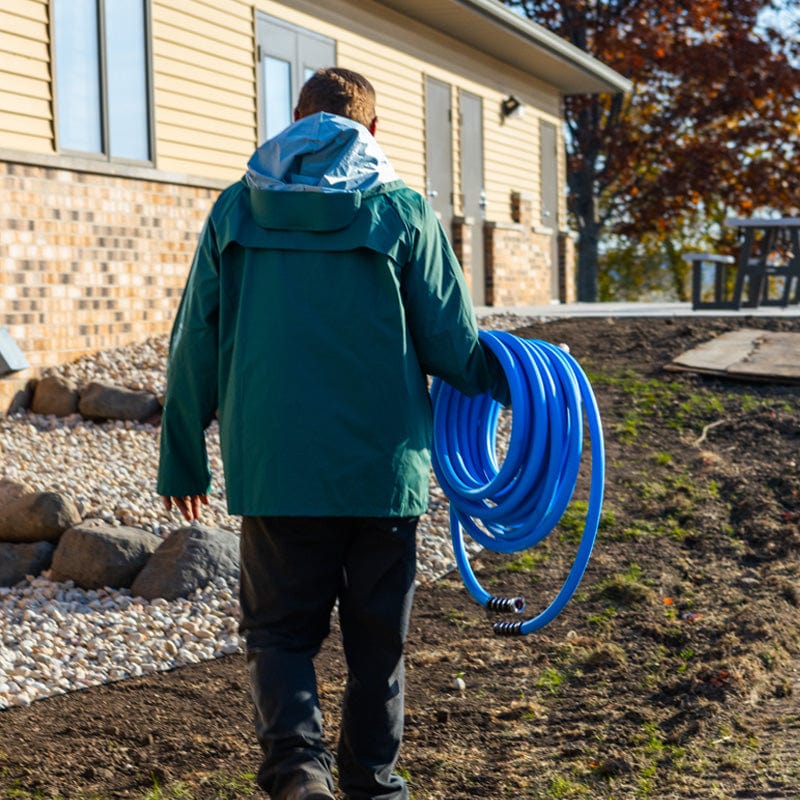 Landscaper carrying a heavy-duty blue hose on a jobsite.