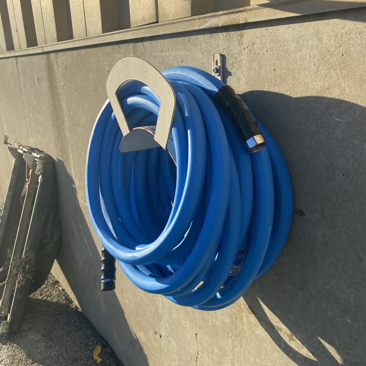 Blue hose coiled on metal hose hanger.