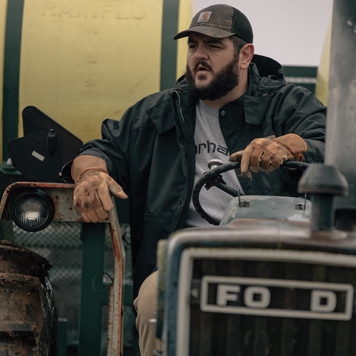 Man wearing Carhartt A513 gloves driving tractor