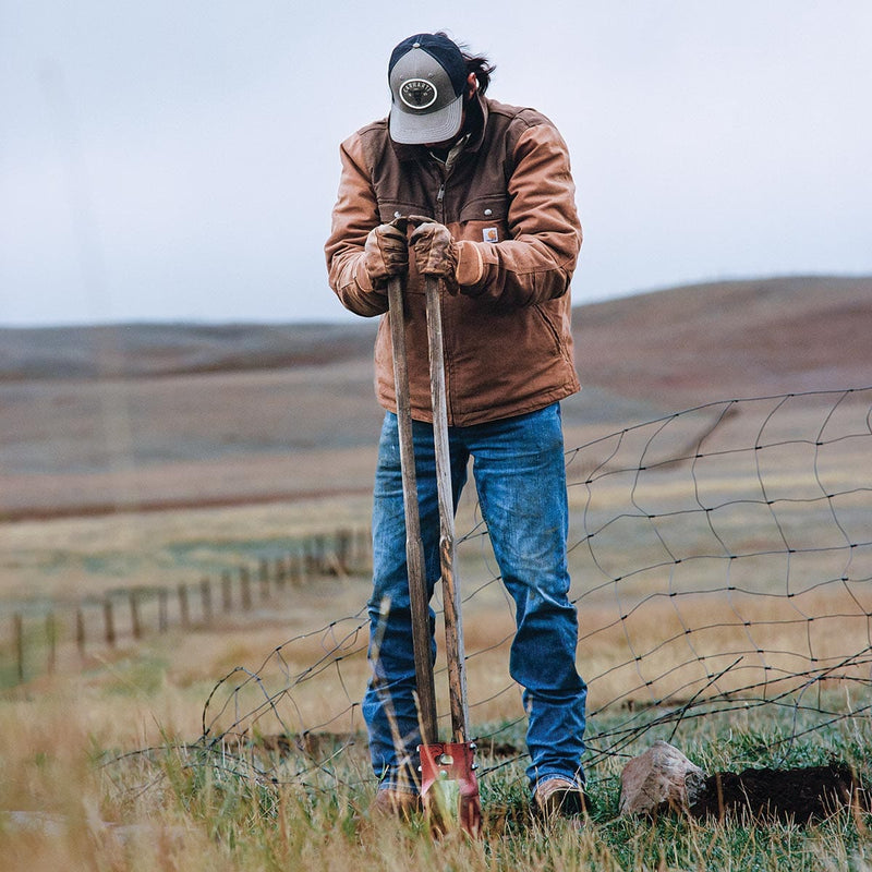 Man wearing Carhartt A513 gloves using a posthole digger