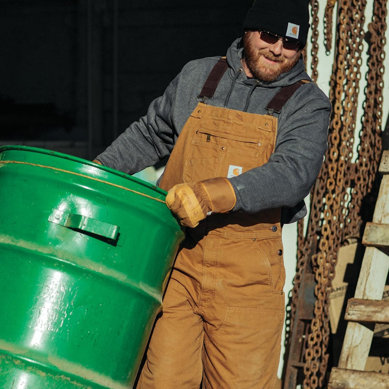 Man wearing Carhartt A513 gloves carrying metal drum