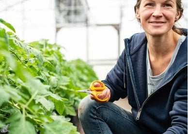 Woman in a greenhouse wearing a sweatshirt