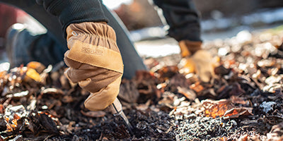A person wearing leather work gloves doing garden work