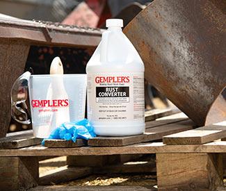A gallon jug of rust converter chemicals with pitcher and rubber gloves 