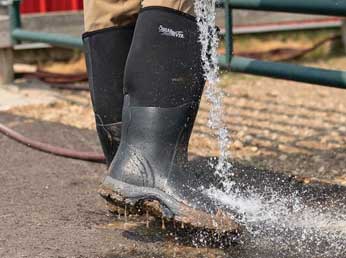 Person rinsing mud off tall chore boots