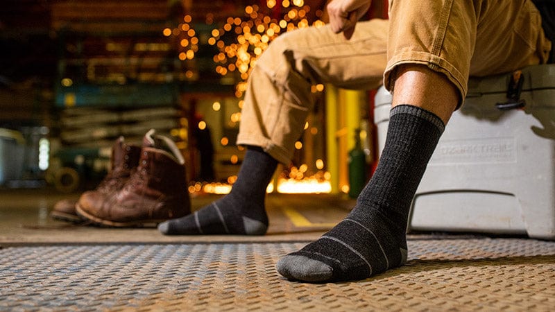 Man with pant legs rolled up to show dark gray socks