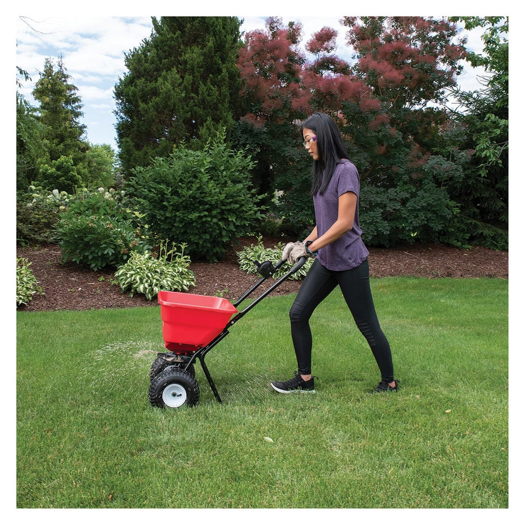 Side view of the Earth Way® 80 lb Broadcast Spreader being used in a yard