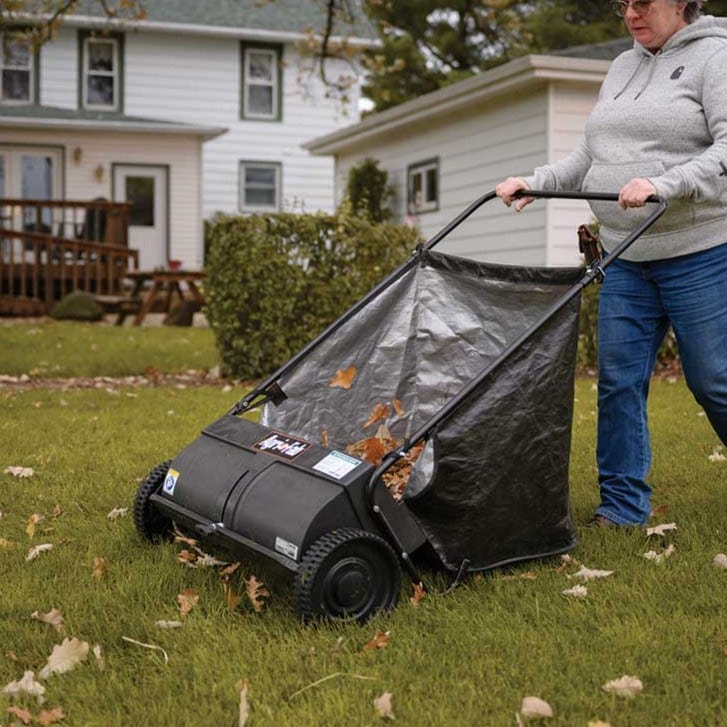 Woman pushing the Agri-Fab 26" Push Lawn Sweeper in a yard