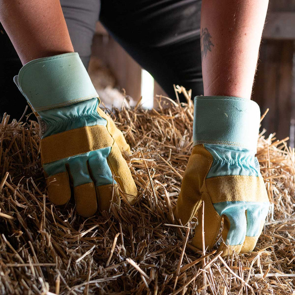 Woman wearing Kinco Women’s Pigskin Leather Work Gloves while lifting straw bale