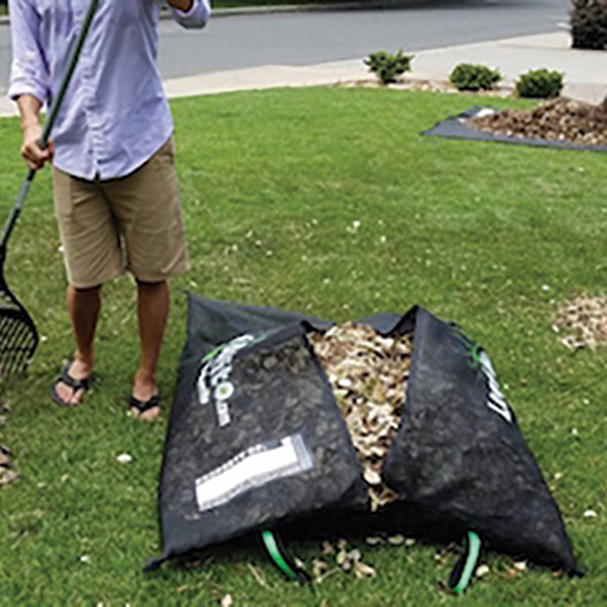 Man raking and filling a Custom Leaf Burrito Pack in a yard